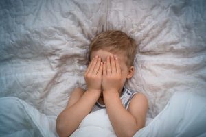 niño tapandose la cara en la cama tras tener terrores nocturnos